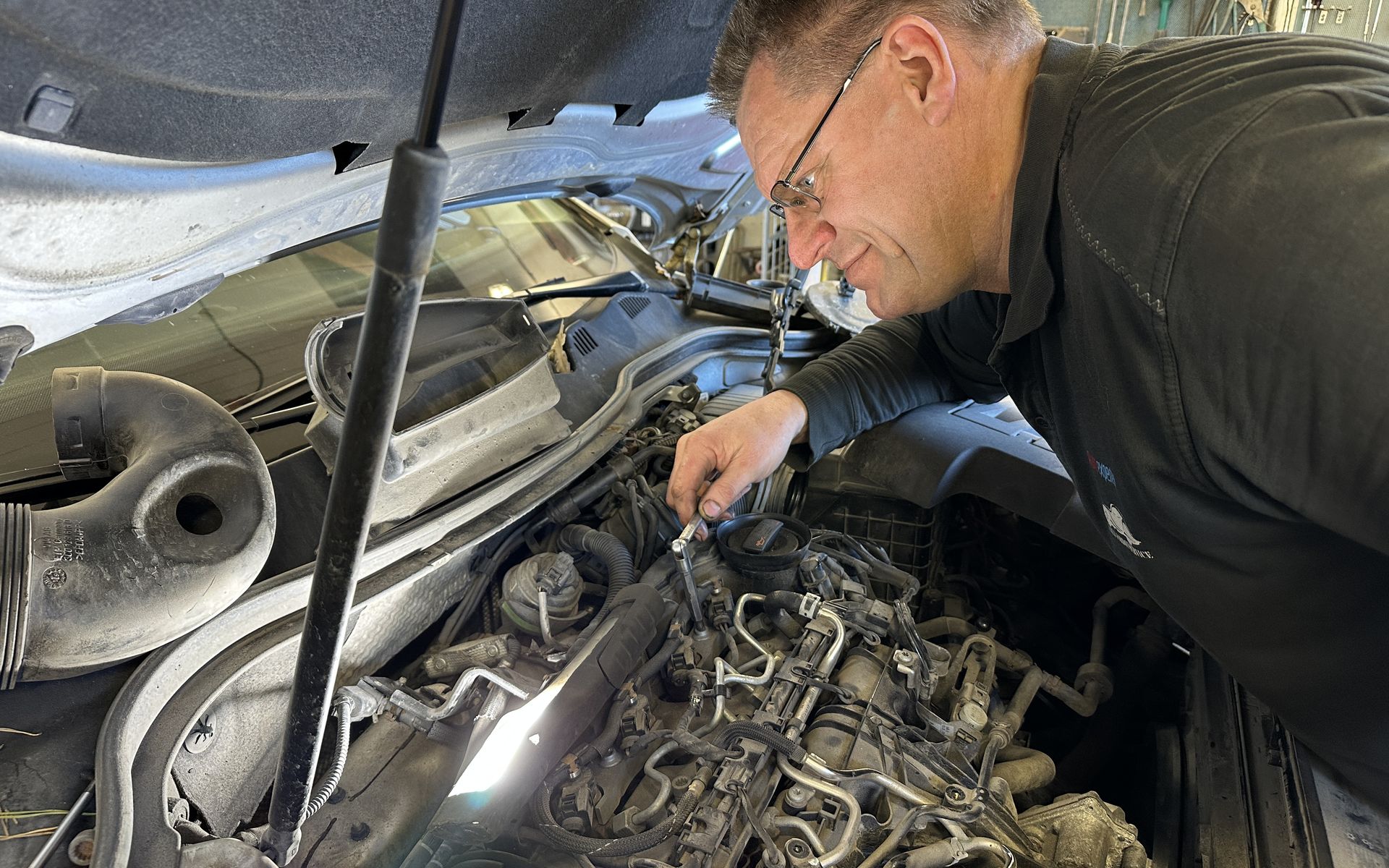 Björn utför service under motorhuven hos Källa Fordonservice