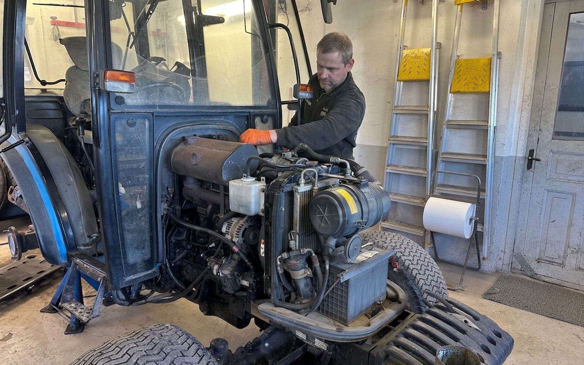 Traktor och gräsklippare på verkstadsgolvet hos Källa Fordonservice